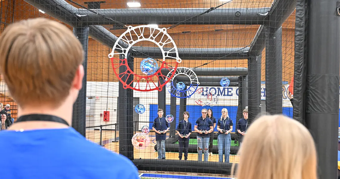 Blue and red drone soccer balls flying toward suspended goal rings
